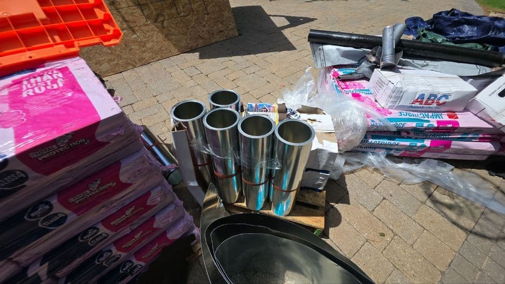 Metal tubes surrounded by construction materials in an outdoor setting.